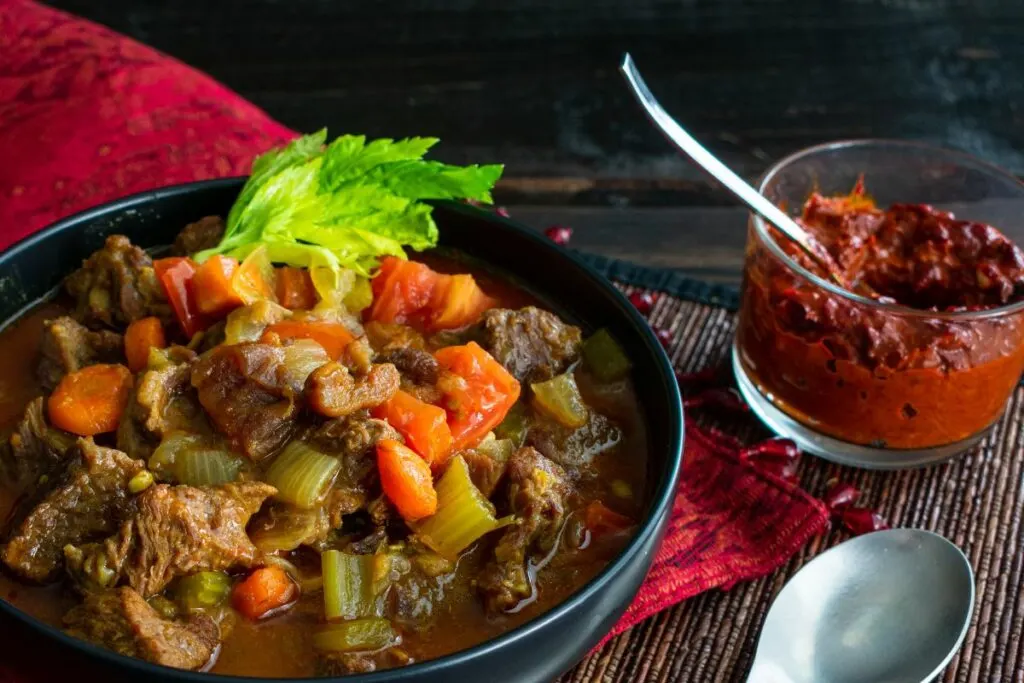 A bowl of moroccan beef stew  with harissa sauce.