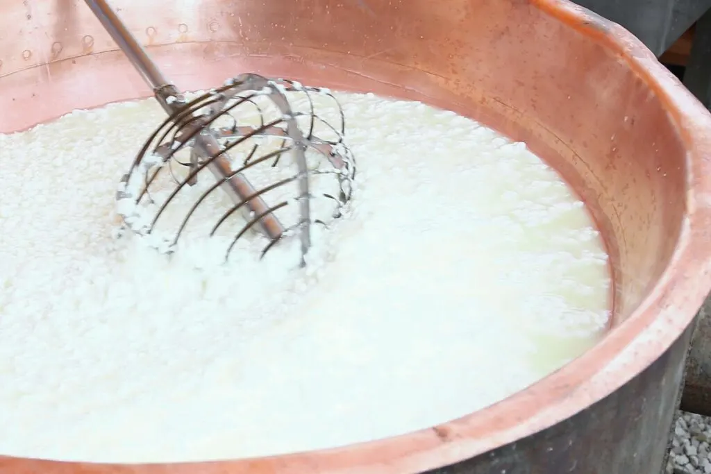 A big bowl of curdled coconut milk being whisked.