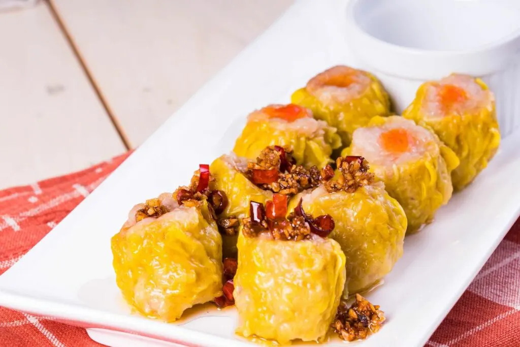 A plate of dim sum with chili garlic sauce.