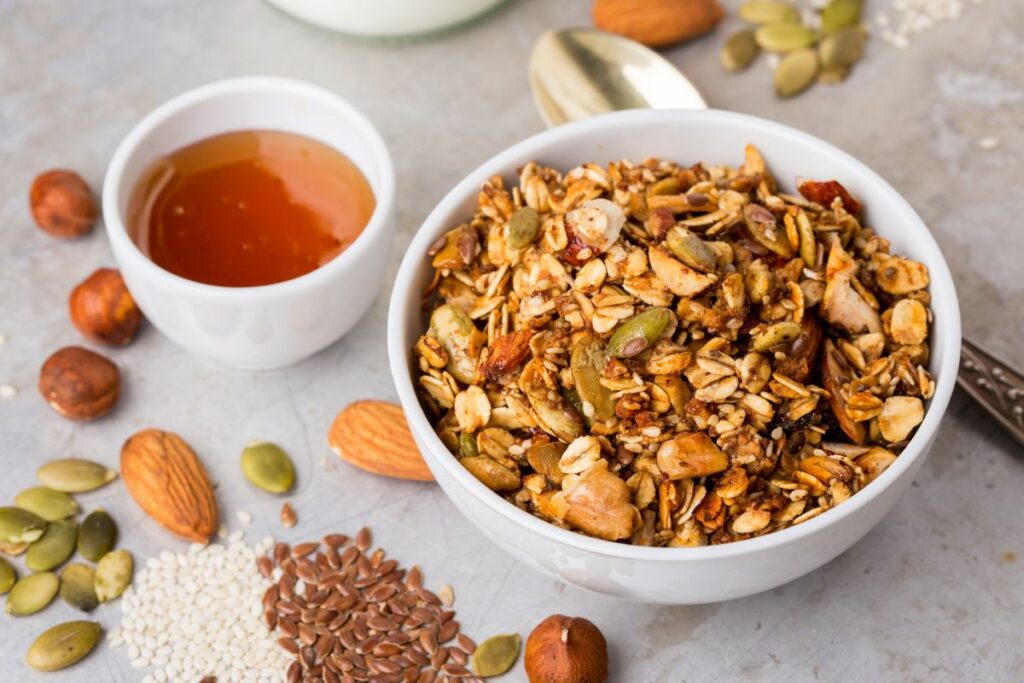 A bowl of granola with a small bowl of agave syrup.