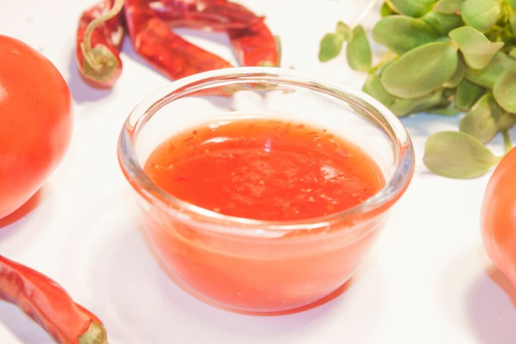 A bowl of homemade sweet chili sauce with its ingredients around it.