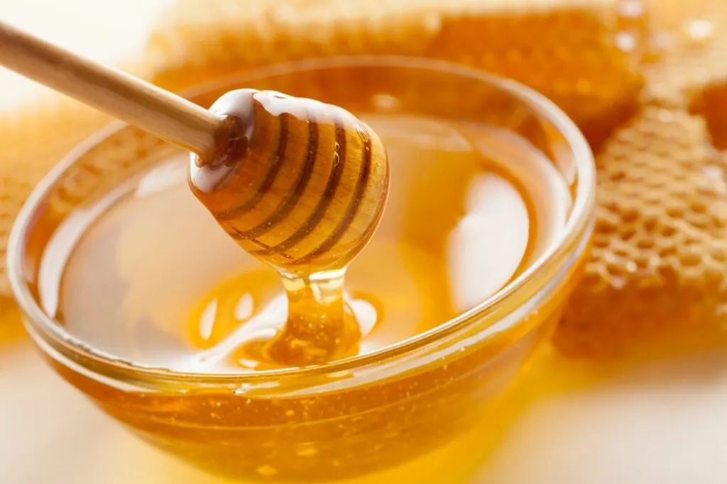 A bowl of raw honey with a honey spoon.