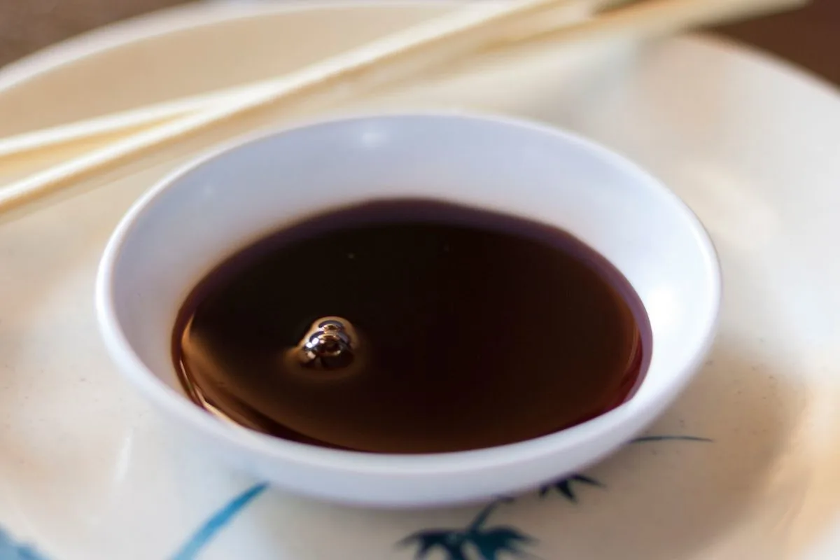 A sauce bowl of kecap manis with chopsticks.