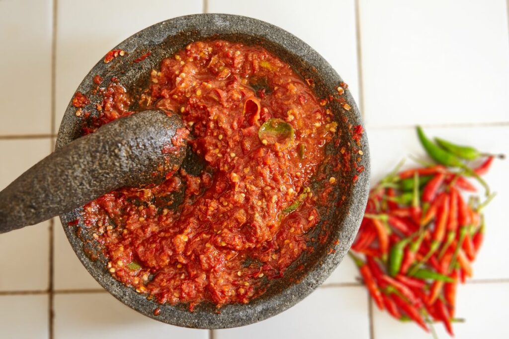 A bowl of sambal oelek and chili on the side.