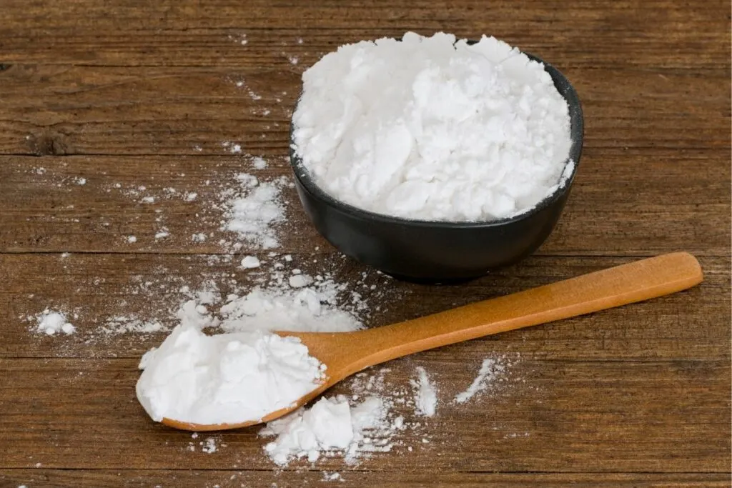 A bowl of arrowroot starch and a wooden spoon of it.