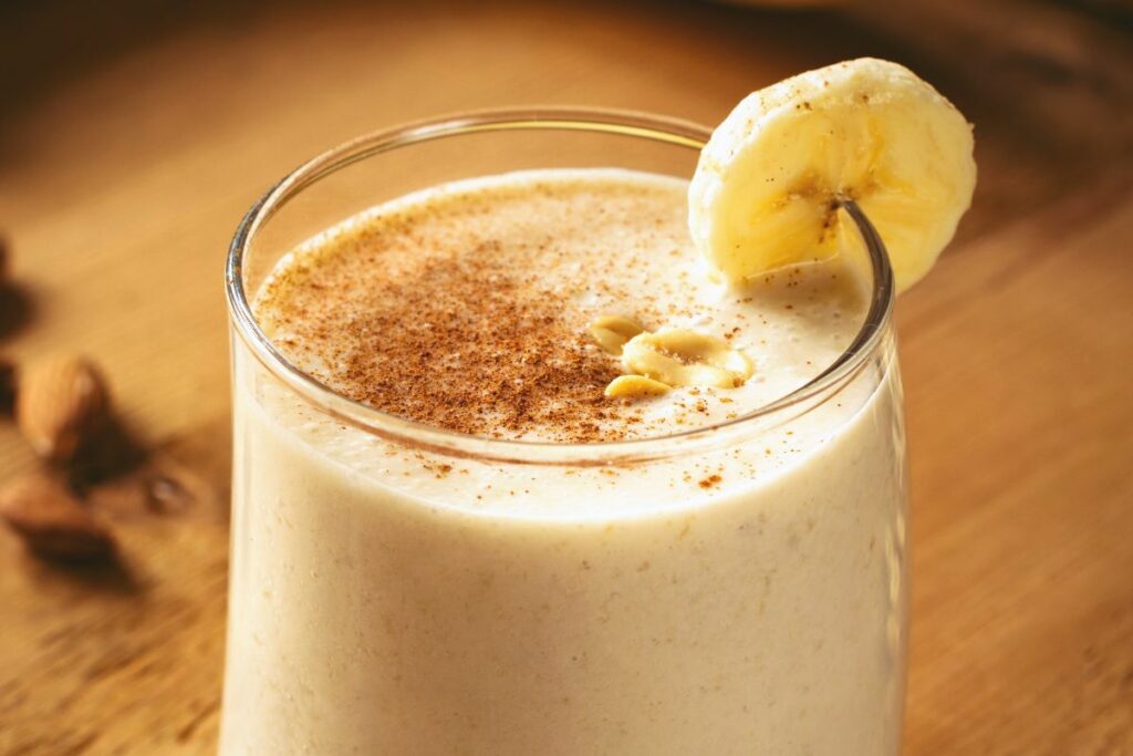 A glass of banana almond butter smoothie with a slice of banana.