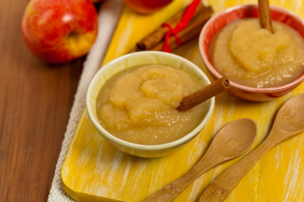 A bowl of homemade applesauce with a cinnamon stick.