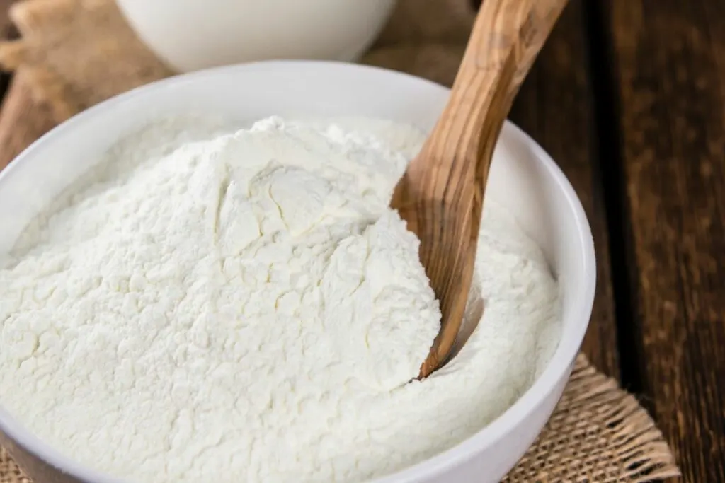 A bowl of xanthan gum with a wooden spoon in it.