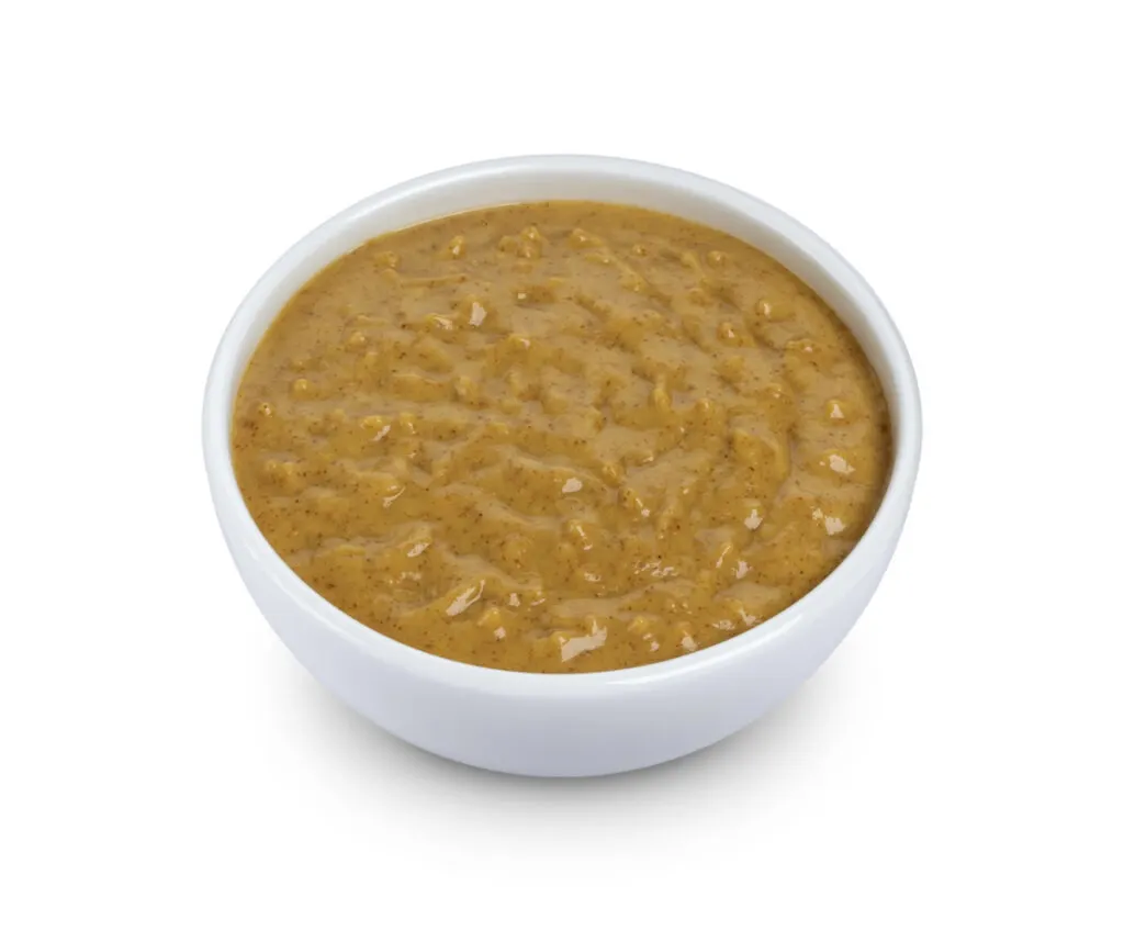 A ceramic bowl of mustard sauce.