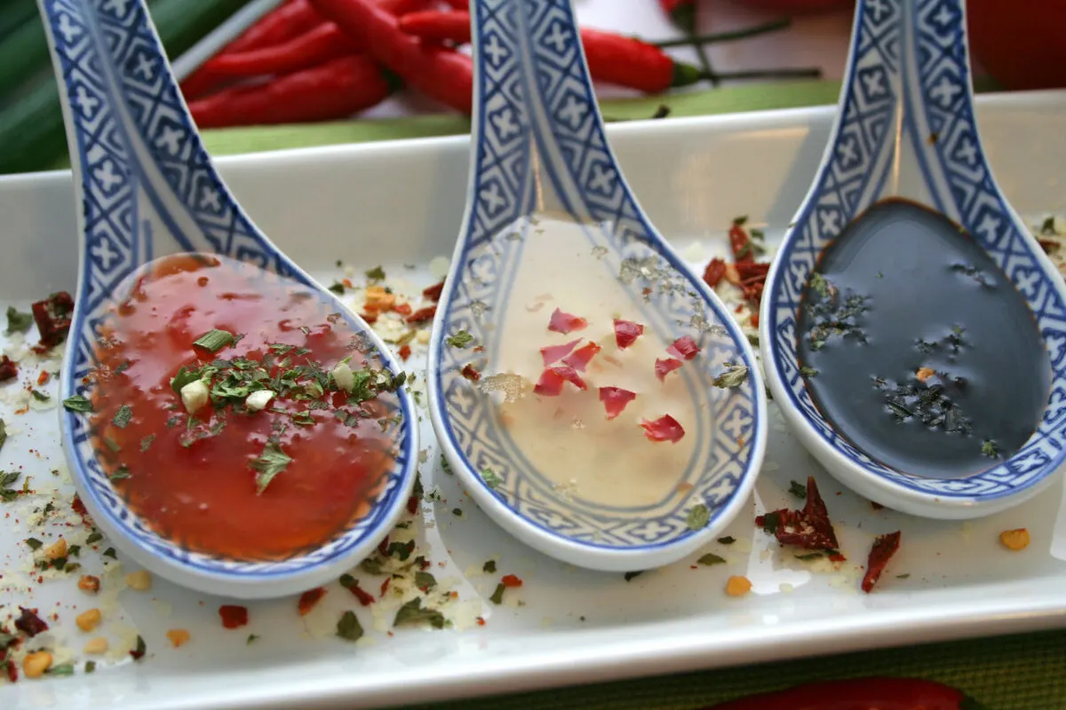 A tray of different Asian sauces on spoons.