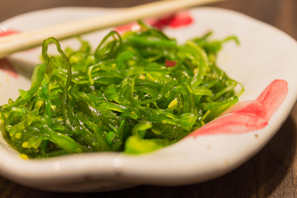 A plate of seaweed with chopsticks.