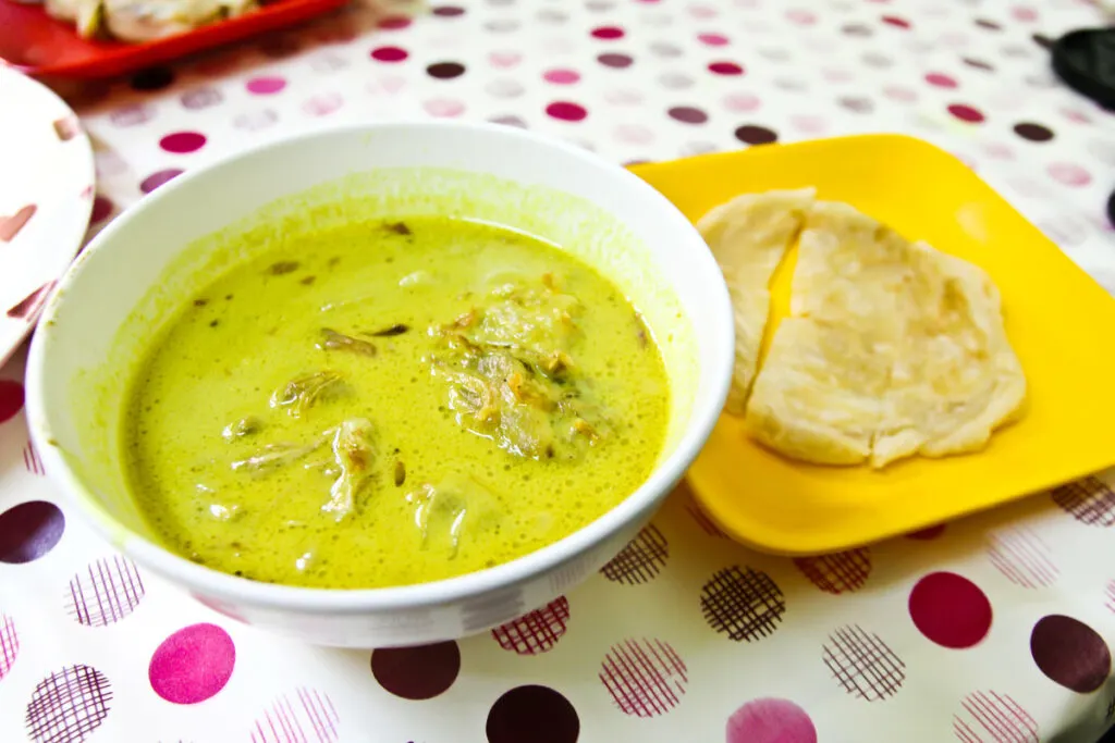 A bowl of spicy beef curry with naan.