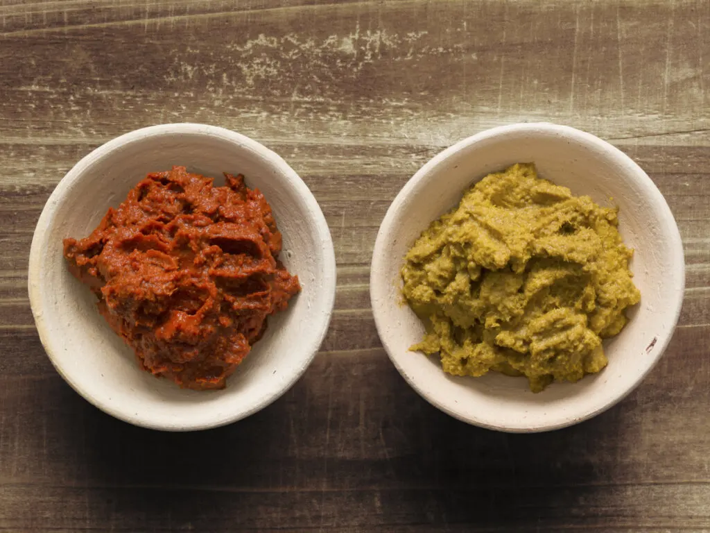 Two bowls of red curry paste and yellow curry paste.