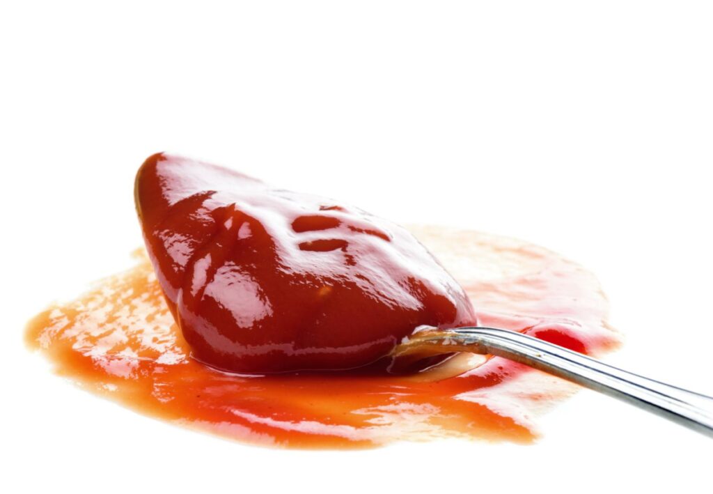 A closeup shot of a spoon of ketchup.
