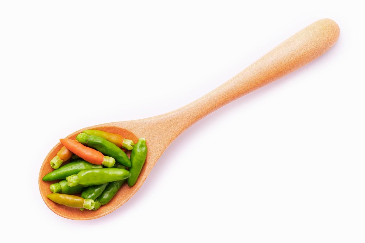 A wooden spoon of different colored Thai bird's eye chili.