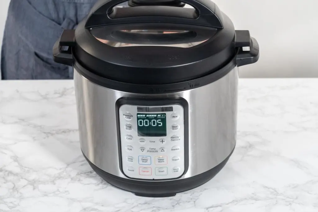 A closeup of a instant pot maker on a marble top.