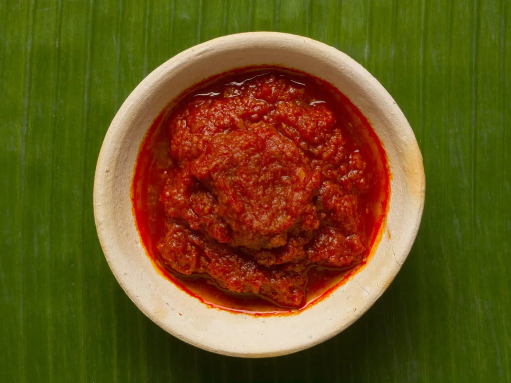 A bowl of sambal chili sauce on a banana leaf.