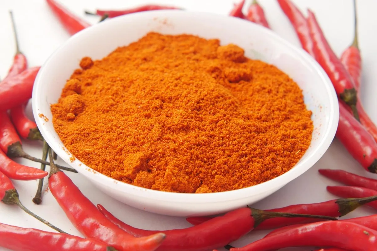 A bowl of fiery chili powder and red chilis scattered around.