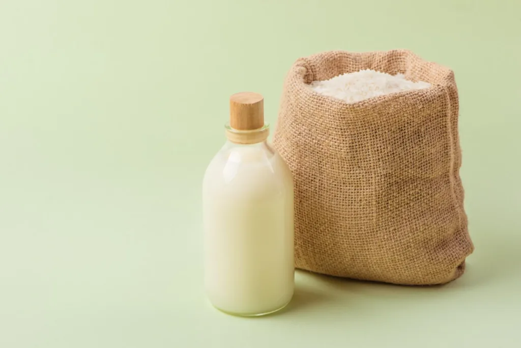 A bottle of rice milk next to a sack of rice.