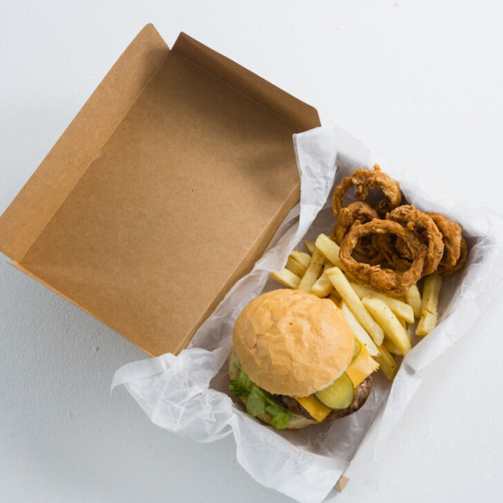 A takeout box of Cook Out's burger and side of onion rings.