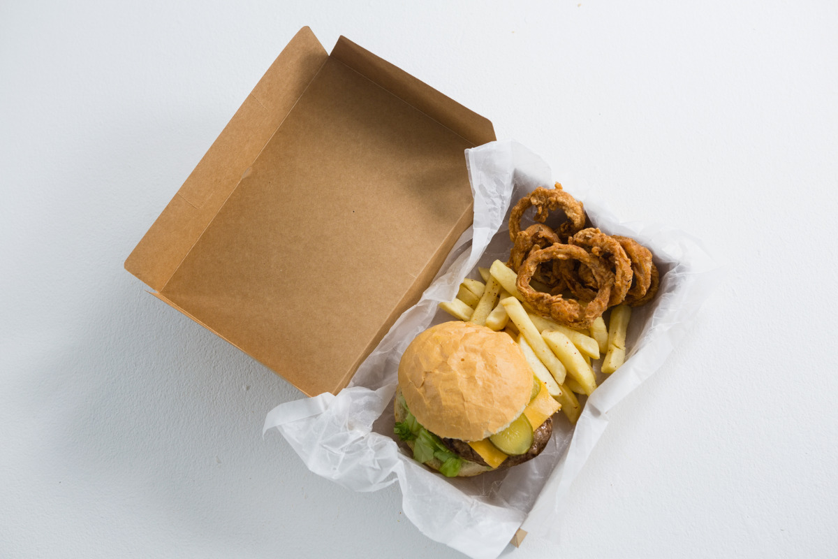 A takeout box of Cook Out's burger and side of onion rings.