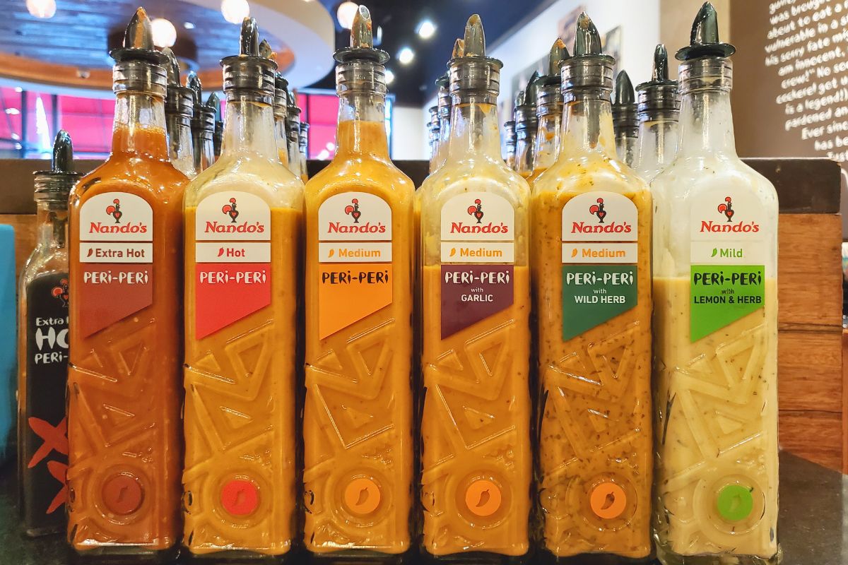 Nando's PERi-PERi bottled sauces labelled with their respective levels of spiciness.
