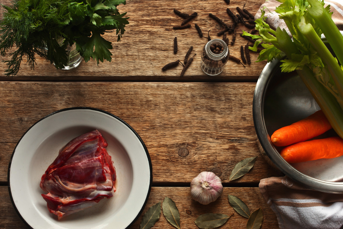 A wooden table of fresh ingredients to make a homemade beef broth.