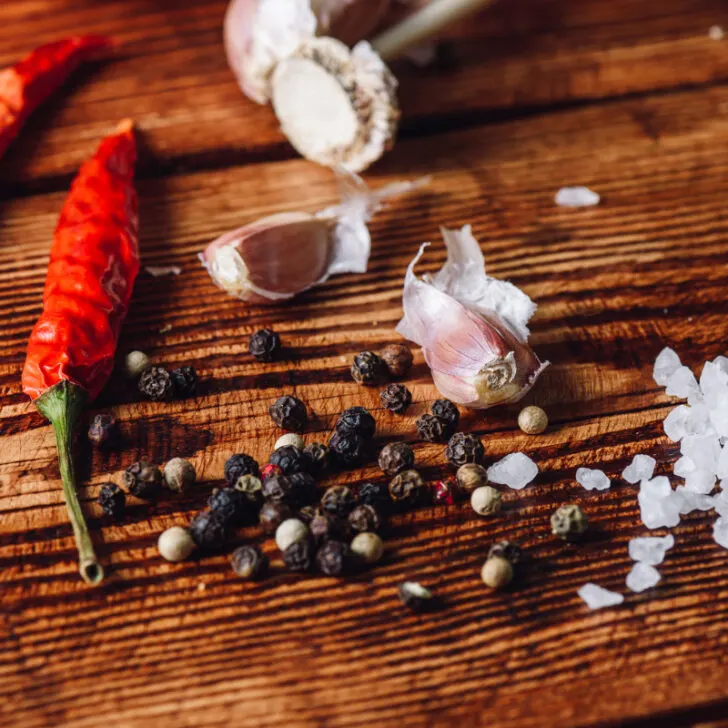A wooden table top with various spicy ingredients scattered across it.