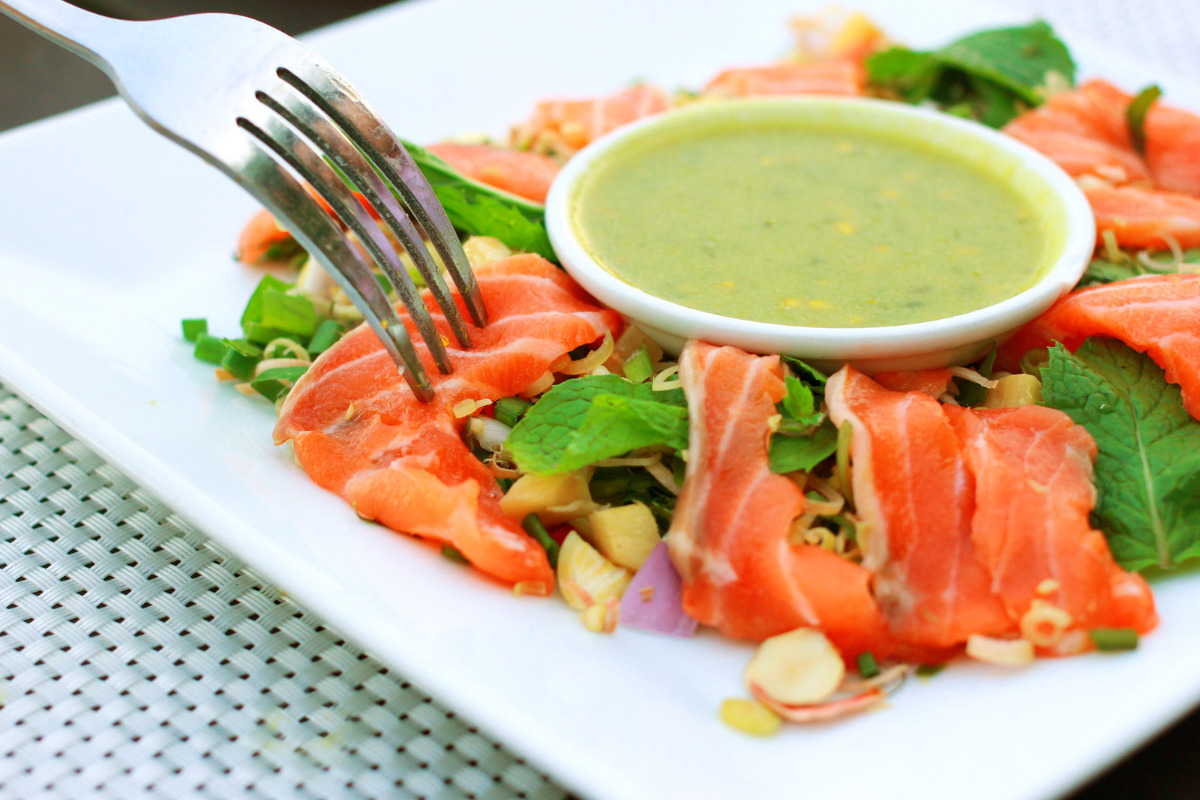 A plate of raw salmon with a sauce bowl of creamy wasabi sauce.