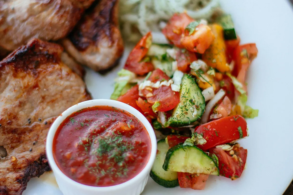 A plate of chicken and vegetables with sriracha sauce.