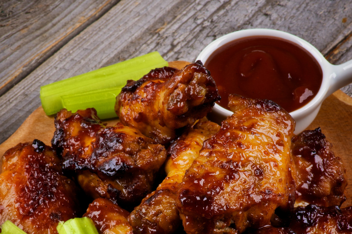 Crispy chicken wings on a plate with BBQ sauce.