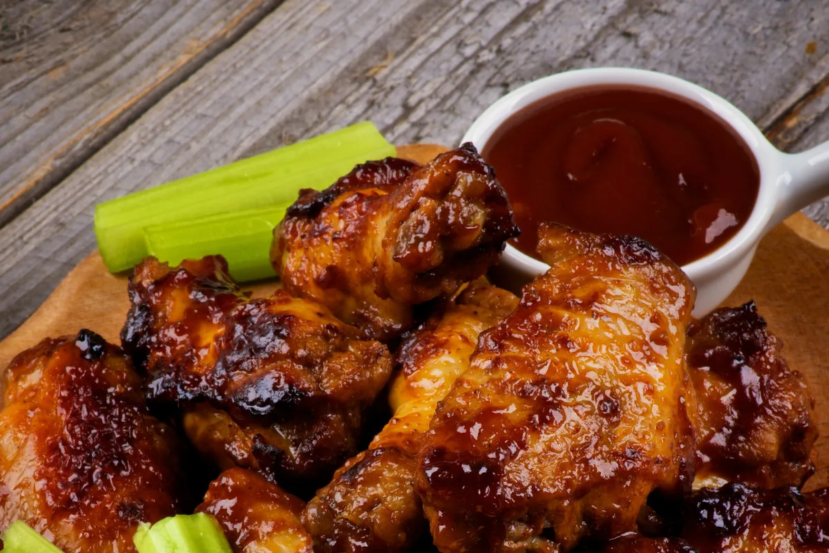 Crispy chicken wings on a plate with BBQ sauce.