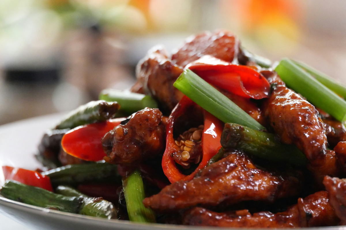 A delicious plate of stir fried chicken with sweet and sour sauce.