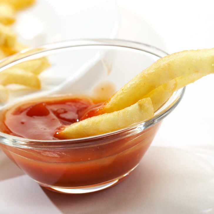 Sauce bowl of ketchup and crispy fries.