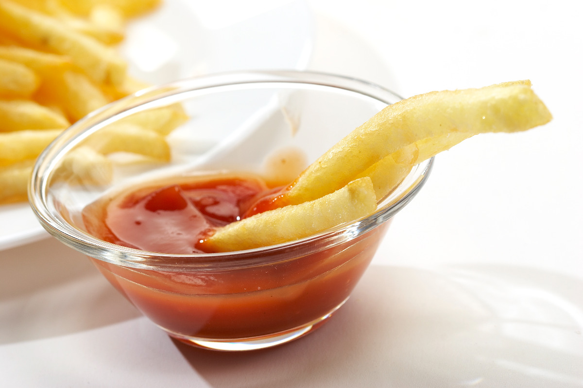 Sauce bowl of ketchup and crispy fries.