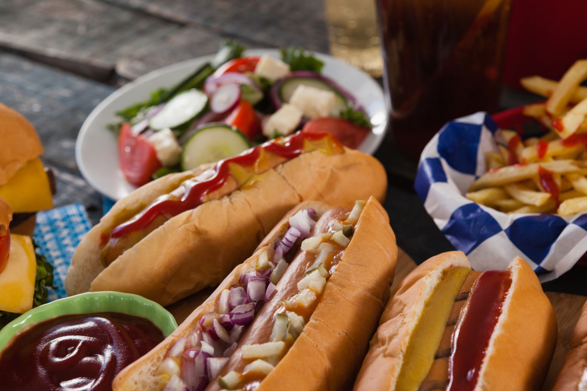 Hotdogs, fries, and a veggie salad served with ketchup.