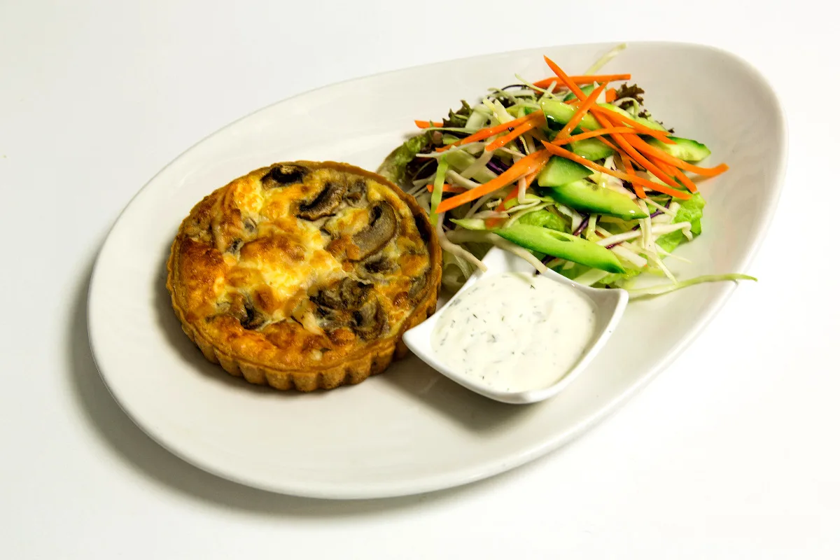 A plate with mayonnaise and a mushroom tart.