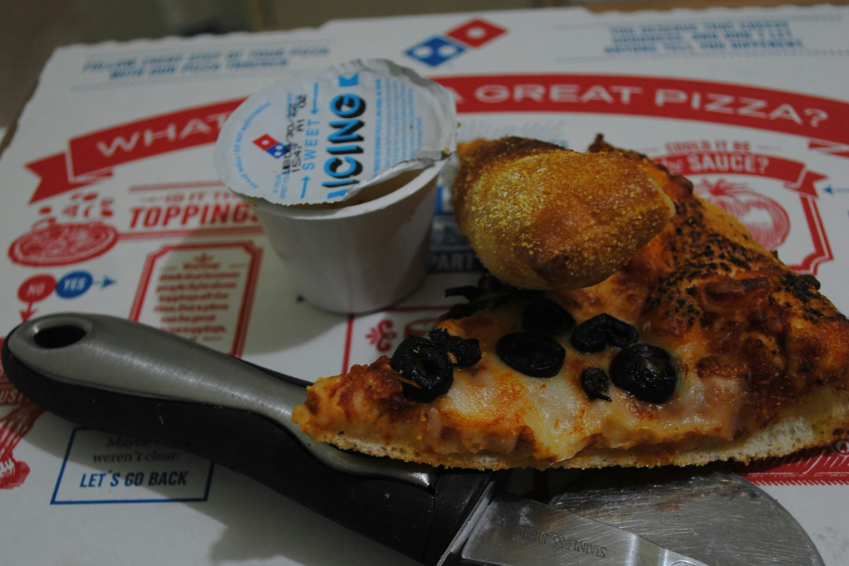 Domino's pizza with an icing dipping sauce cup.