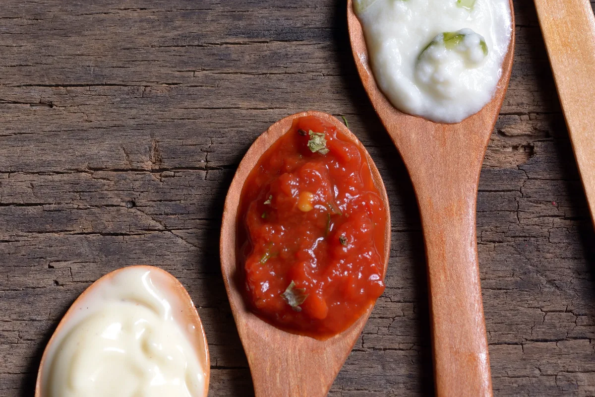 Row of spoons with mother sauces on them.